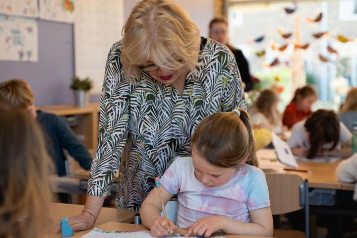 Onderwijsambassadeur Toineke Helpt Een Leerling Staand LR