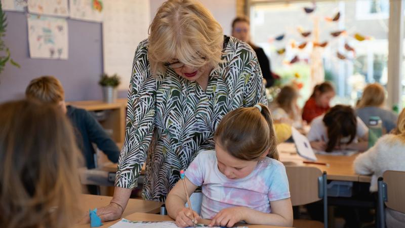Onderwijsambassadeur Toineke Helpt Een Leerling Staand LR